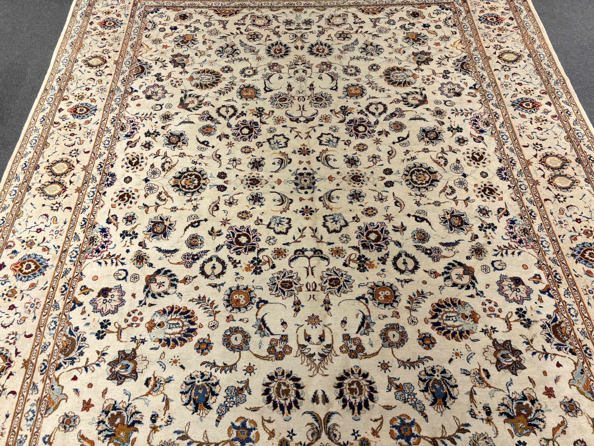 A Kashan ivory ground carpet, central field of foliate motifs, multi bordered, 400 x 308cm, Please note this lot attracts an additional import tax of 5% on the hammer price